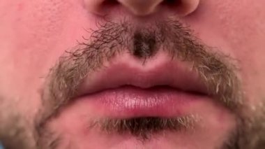 Tıraşsız bir adamın ağzı kırmızı domates soslu kızarmış patates yerken. Adam mavi arka planda soslu kızarmış patates yiyor. Fast food restoranında yanlış yemek.