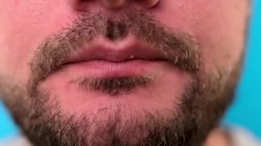 Tıraşsız beyaz adam tavuk etiyle kemik kemiriyor. Restoranda sağlıksız yemekler yiyor. Fast food yiyen bir adamın yakın çekimi, çıtır çıtır tavuk kanatları..