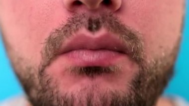 Fast food yiyen bir adamın yakın çekimi, çıtır çıtır tavuk kanatları. Tıraşsız beyaz adam tavuk etiyle kemik kemiriyor. Restoranda sağlıksız yemekler yiyor..