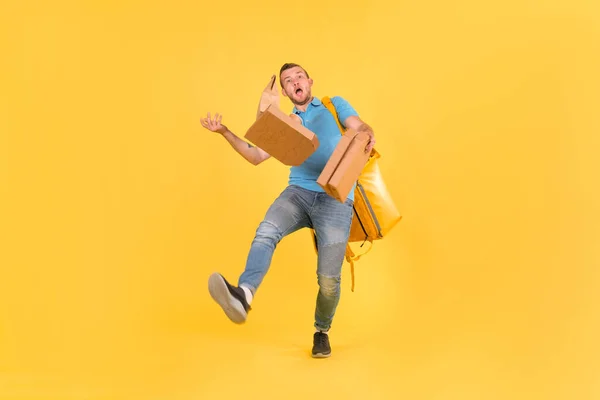 Delivery guy in blue uniform slipped and lost his balance and threw boxes of food from restaurant in direction. Clumsy food delivery guy broke up an order for customer. Poor product delivery.