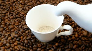 Kahve fincanında, kahve çekirdekleri ve ahşap arka planda.