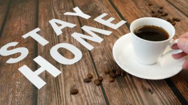 Bir kupa kahve, kahve çekirdeği ve kelimeler evde kalır, koronavirüs konsepti, kişisel karantina konsepti.