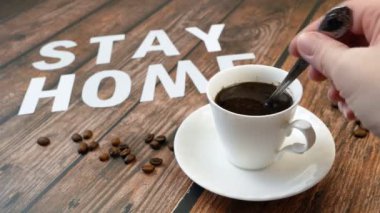 Bir kupa kahve, kahve çekirdeği ve kelimeler evde kalır, koronavirüs konsepti, kişisel karantina konsepti.
