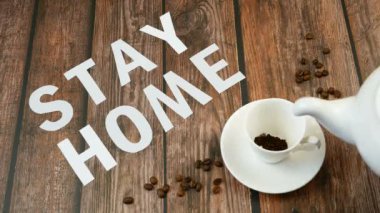 Bir kupa kahve, kahve çekirdeği ve kelimeler evde kalır, koronavirüs konsepti, kişisel karantina konsepti.