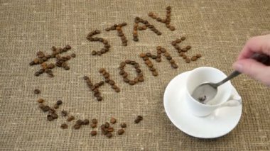Bir kupa kahve, kahve çekirdeği ve kelimeler evde kalır, koronavirüs konsepti, kişisel karantina konsepti.