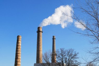 Mavi gökyüzünde gri dumanlı bitki tüpleri, mavi gökyüzüne karşı nükleer enerji santrallerinin kimyasal kuleleri