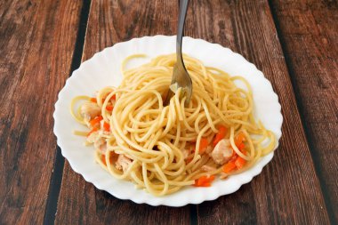 Beyaz tabak üzerine tavuk parçalı spagetti bolonezi, siyah ahşap arka plan, İtalyan makarnası, yakın plan.