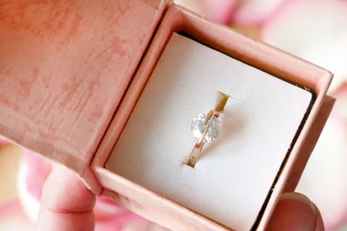 Güzel pembe güller, taç yaprakları ve elmas yüzük ahşap arka planda hediye.