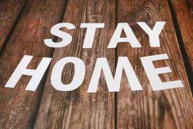 Evde kal, beyaz kağıttan, ahşap arka plandan, Coronavirus covid 'den, konsept 19' dan koruma önleminden uzak dur.