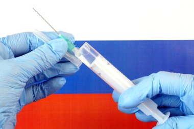 Covid - 19, koronavirüs konsepti. Rus Federasyonu bayrağında şırınga ve koronavirüs salgını içeren tıbbi eldiven verin.