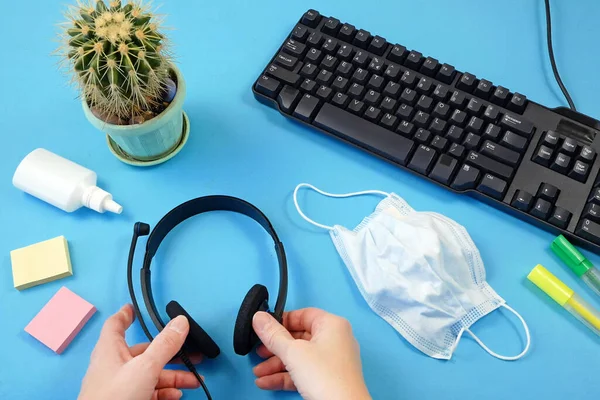 Woman sanitize workplace. Hands disinfection. Plant, keyboard, pen, medical mask, headphones and hand sanitizer. Coronavirus COVID-19 concept. Top view