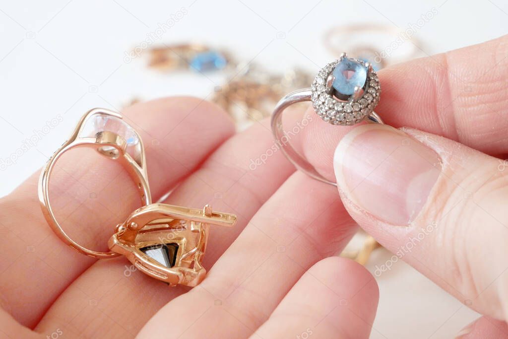 hand takes ring with big blue topaz and white diamonds around, jeweler looking at jewelry through magnifying glass, jewerly inspect and verify, pawnshop concept