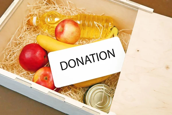 Donation food concept, wooden box with products, free delivery concept, fruits, oil in bottle and canned food, food drive