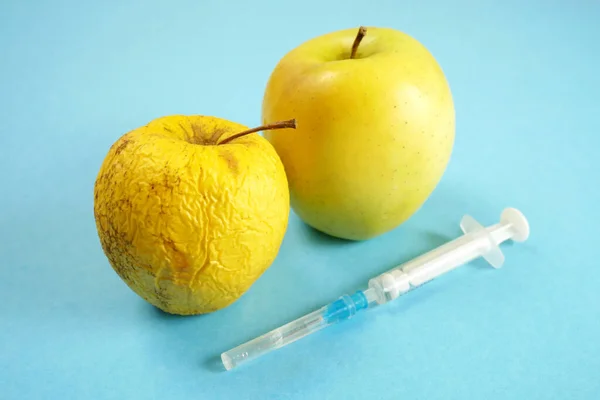Genetycznie Zmodyfikowane Żółte Jabłko Strzykawkami Niebieskim Tle Stare Jabłko Gmo — Zdjęcie stockowe