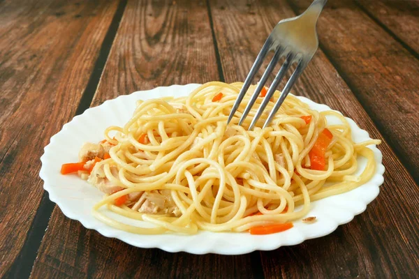 Spaghetti bolognese with chicken pieces on white plate on dark wooden background, italian pasta
