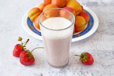 Sulu çilek ve kayısı arkaplanlı taze meyveli milkshake.