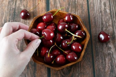 Tahta arka plandaki kirazların içindeki kirazlardan taze ve sulu bir kiraz al. Üst görünüm, yakın plan
