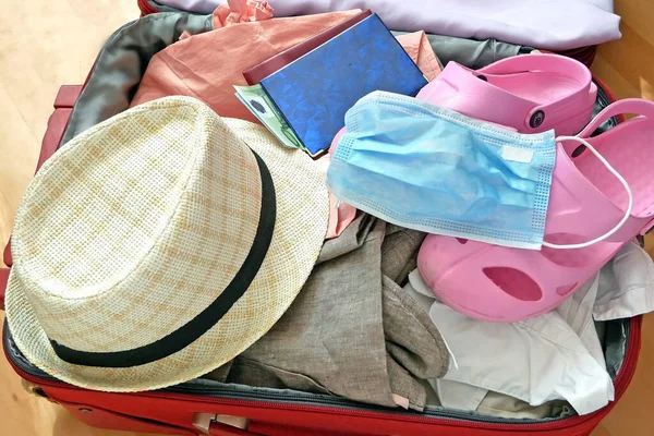 travel suitcase, sun hat, passports and medical mask on wooden background, flat lay, problems in the tourism business, covid - 19, coronavirus concept