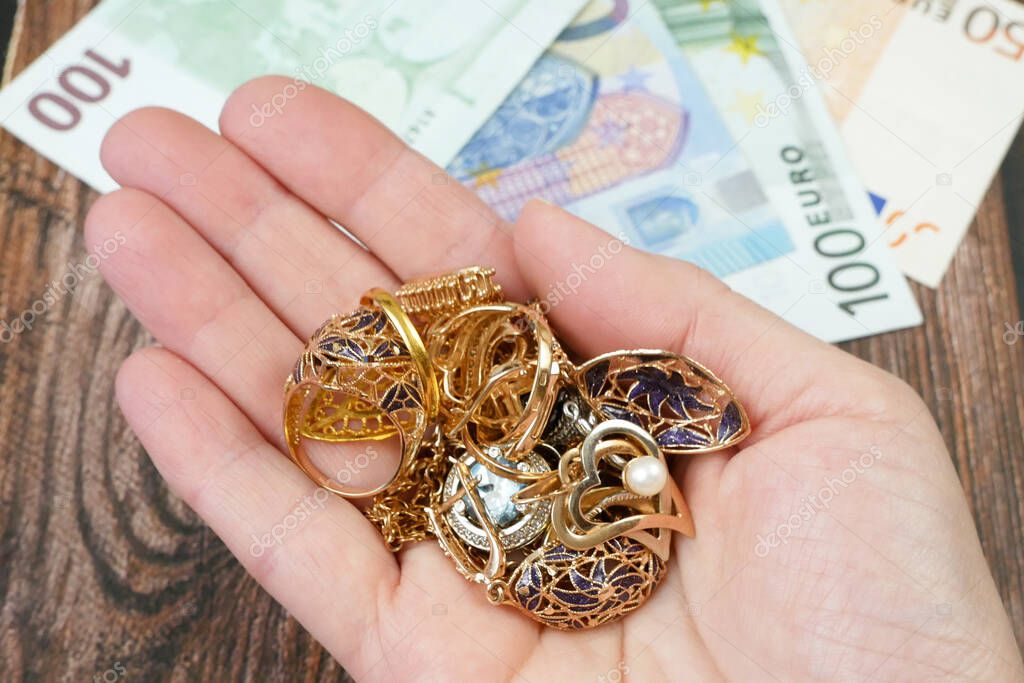 earring in hand, many golden and silver jewerly and money, pawnshop concept, jewerly shop concept