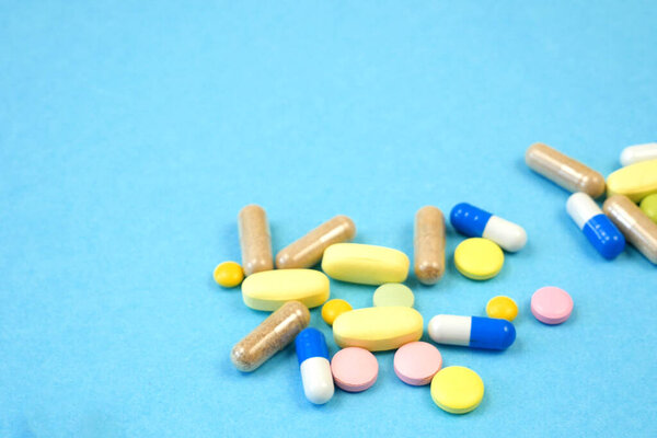 many pills, capsules and drug on blue bakcground, closeup