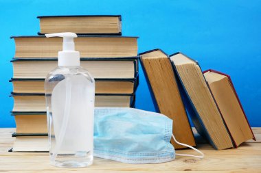 Okula Dönüş Coronavirus Covid-19, kitap yığını, dezenfektan ve tıbbi maske.
