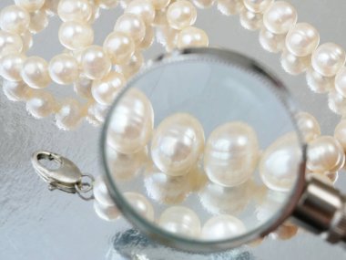 Kuyumcu büyüteçle inci kolyeye bakıyor, mücevher kontrolü ve doğrulama, rehinci konsepti, kuyumcu dükkânı konsepti.