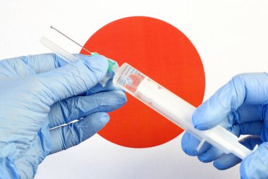 Aşılı şırınga, Japon bayrağının arka planında bir eldivende, Coronavirus 'a karşı aşı, Warp Hızı Operasyonu