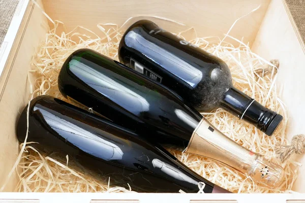 glass and bottle of expensive elite wine in a wooden box with shavings, wine tasting, online order and delivery wine in coronavirus time, internet wine shops concept