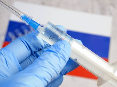 Aşılı şırınga, Rusya Federasyonu bayrağının arka planında bir eldivende, Coronavirus 'a karşı aşı, Warp Hızı Operasyonu