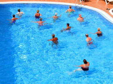 İnsanlar yüzme havuzunda su sporu yapıyor. Tatil köyünde turizm, koronavirüs zamanı konsepti.