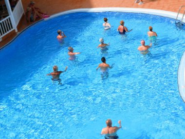 İnsanlar yüzme havuzunda su sporu yapıyor. Tatil köyünde turizm, koronavirüs zamanı konsepti.