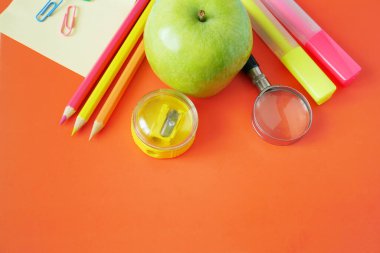 Okula, kitap yığınlarına, kalemlere, elmaya, küreye ve elmaya karatahta üzerine.
