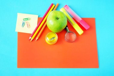 Okula, kitap yığınlarına, kalemlere, elmaya, küreye ve elmaya karatahta üzerine.