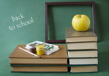 Elmalı, küreli, kalemli ve okul tahtasındaki kalemli kitap yığını. Öğretmenler Günü konsepti