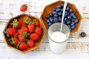 Muzlu, yaban mersinli, çilekli ve sütlü meyve püresi yapıyorum. Meyve suyu yapmak için taze meyvelerle dolu blender. 