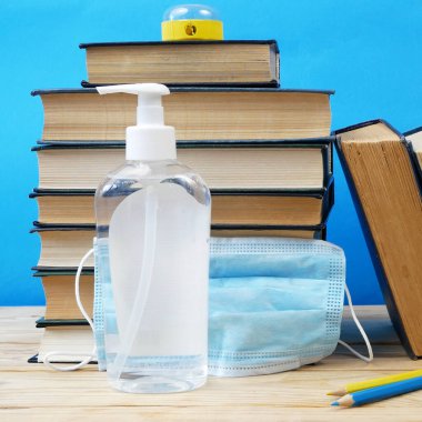 Okula Dönüş Coronavirus Covid-19, kitap yığını, dezenfektan ve tıbbi maske.