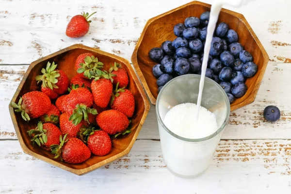 Muzlu, yaban mersinli, çilekli ve sütlü meyve püresi yapıyorum. Meyve suyu yapmak için taze meyvelerle dolu blender. 