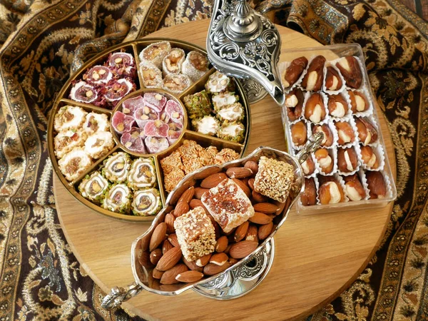 Eastern sweets with nuts, candy, metal vase, dates on wooden background