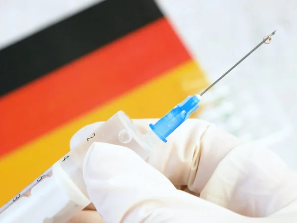 Jeringa Con Una Vacuna Sostiene Mano Guante Fondo Bandera Alemania — Foto de Stock