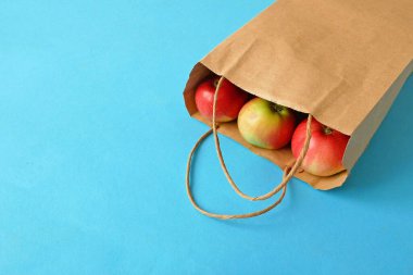 mavi arkaplanda kırmızı elma ve kağıt torba, yeşil market 