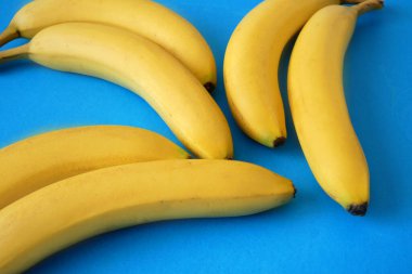 Mavi üzerine taze sarı muzlu soyut arkaplan, yakın plan.