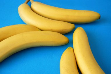 Mavi üzerine taze sarı muzlu soyut arkaplan, yakın plan.