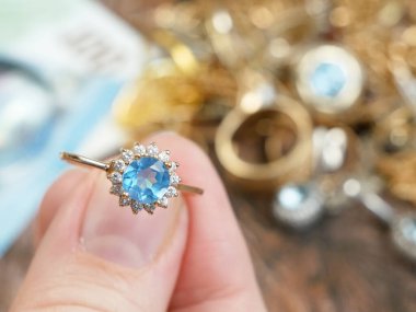 Eline büyük bir topaz taşı, bir sürü elmas, altın, gümüş ve para mücevheri, rehinci konsepti, yakın plan...