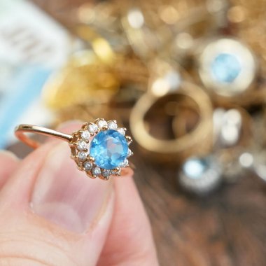 Eline büyük bir topaz taşı, bir sürü elmas, altın, gümüş ve para mücevheri, rehinci konsepti, yakın plan...