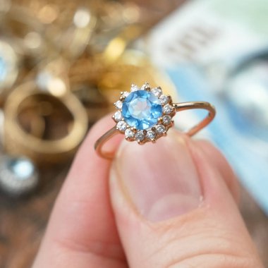 Eline büyük bir topaz taşı, bir sürü elmas, altın, gümüş ve para mücevheri, rehinci konsepti, yakın plan...