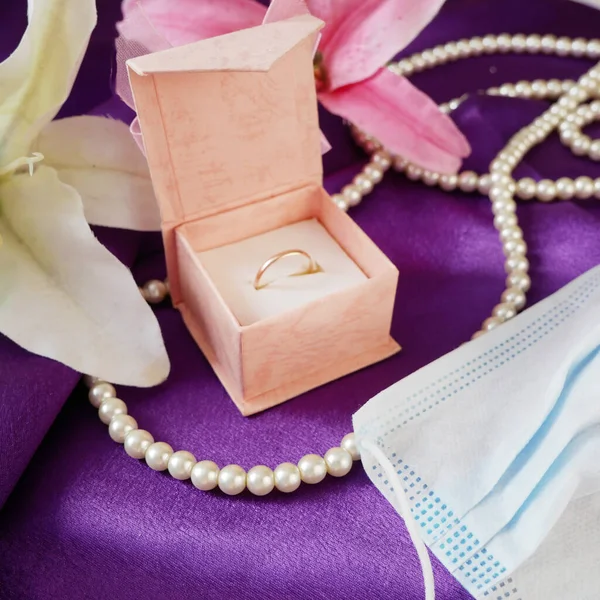 Geschenkbox Blaue Medizinische Maske Goldene Eheringe Perlenkette Und Rosa Blumenstrauß — Stockfoto