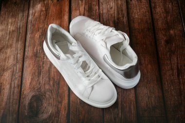 Ahşap arka planda beyaz modern spor ayakkabı çifti, yakın plan.,