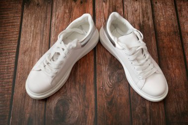 Ahşap arka planda beyaz modern spor ayakkabı çifti, yakın plan.,