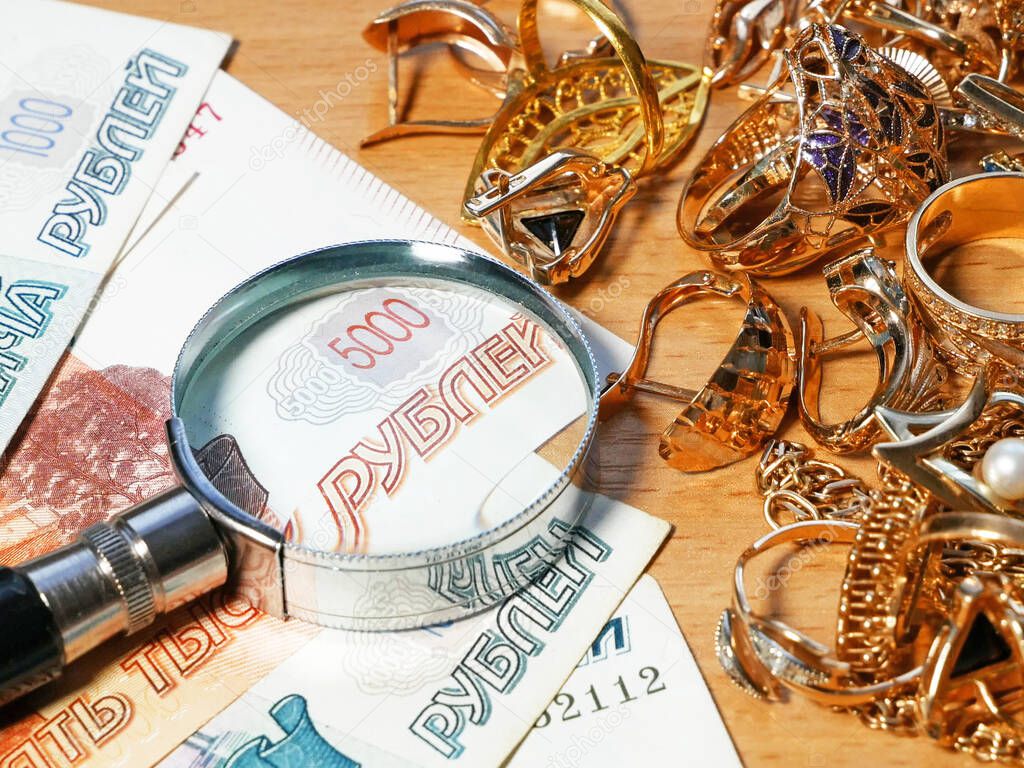 jewelry scrap of gold and silver and money, pawnshop concept jeweler looking at jewelry through magnifying glass, jewerly inspect and verify, closeup