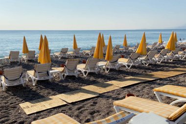 Empty beach with sun loungers and sunbathing areas and sea in sunny summer day, calm video, outdoors